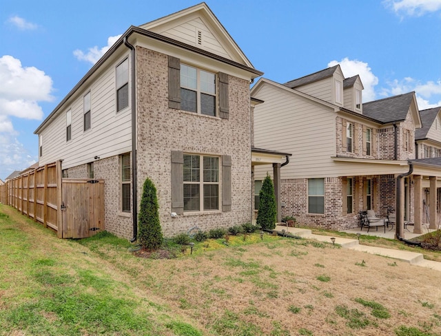 back of property with brick siding, a lawn, and a patio area