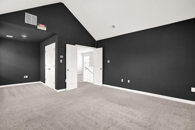 carpeted spare room with visible vents, baseboards, and high vaulted ceiling