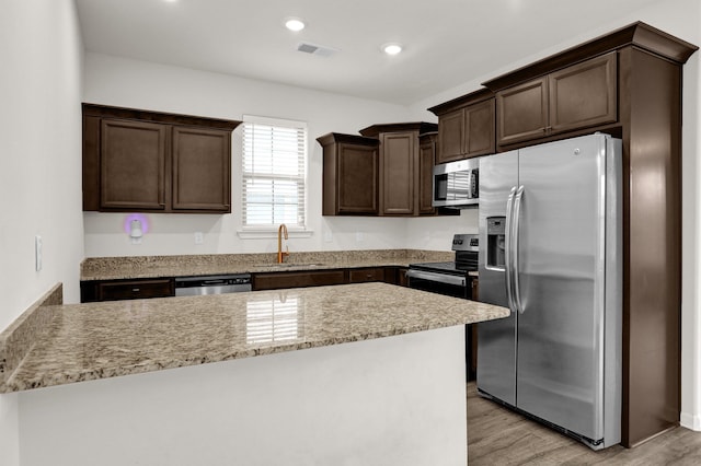 kitchen featuring recessed lighting, a sink, dark brown cabinetry, light wood-style floors, and appliances with stainless steel finishes