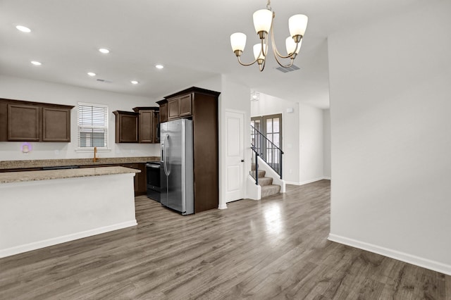 kitchen featuring wood finished floors, visible vents, freestanding refrigerator, dark brown cabinetry, and a notable chandelier