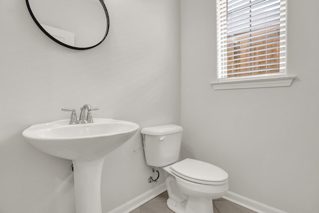 half bathroom with tile patterned floors, toilet, and baseboards