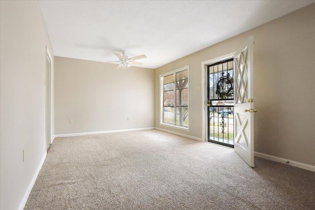 carpeted spare room featuring baseboards and ceiling fan