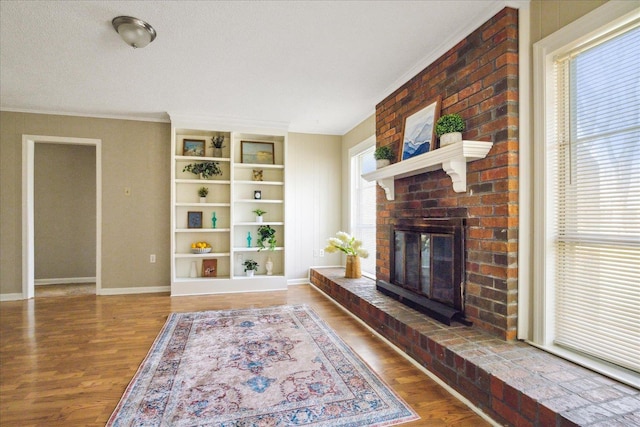 living area featuring ornamental molding, a fireplace, baseboards, and wood finished floors