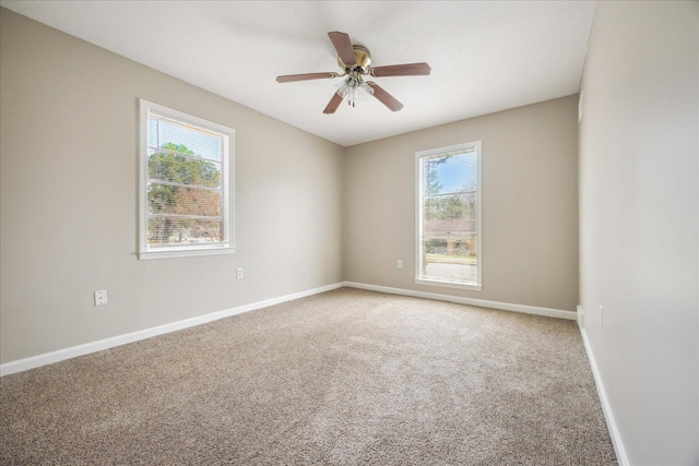 unfurnished room with a ceiling fan, light colored carpet, and baseboards