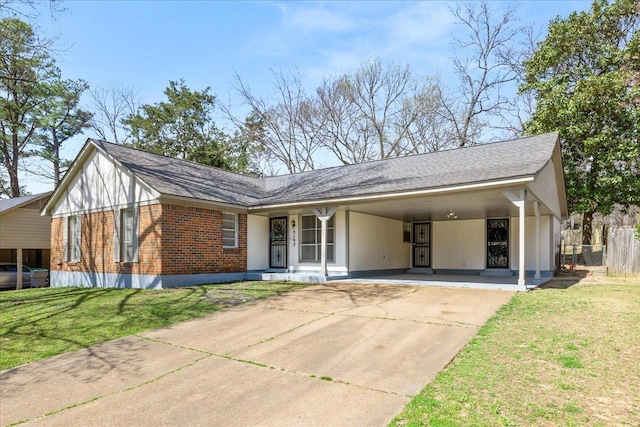 view of front of house with an attached carport, a front yard, fence, driveway, and brick siding