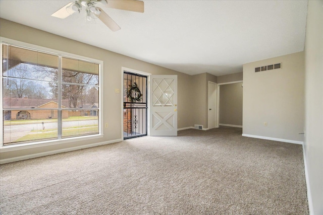 carpeted empty room with visible vents, baseboards, and a ceiling fan