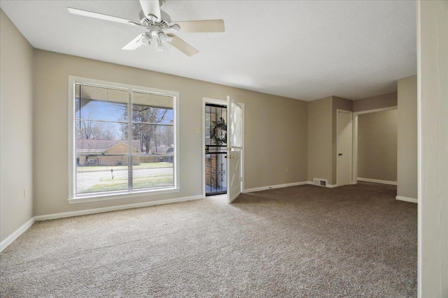 carpeted spare room with visible vents, a ceiling fan, and baseboards