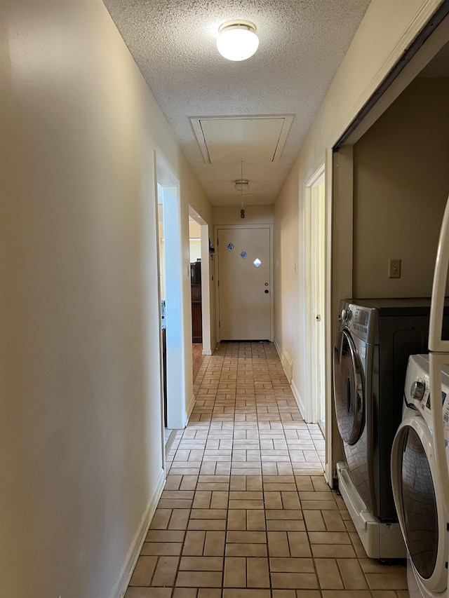 washroom with a textured ceiling, separate washer and dryer, baseboards, attic access, and laundry area