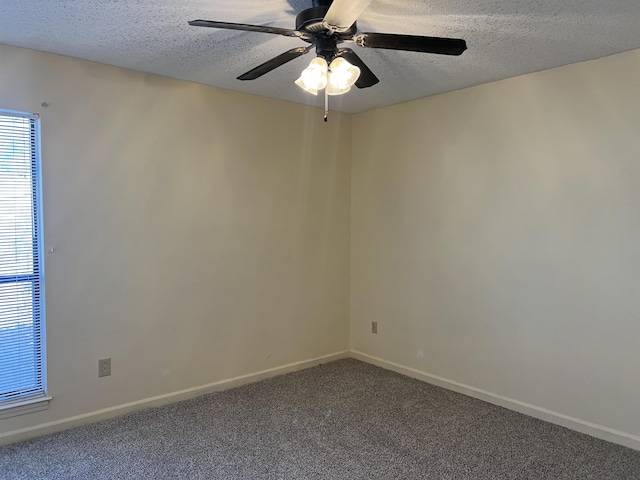 empty room with a ceiling fan, baseboards, a textured ceiling, and dark carpet