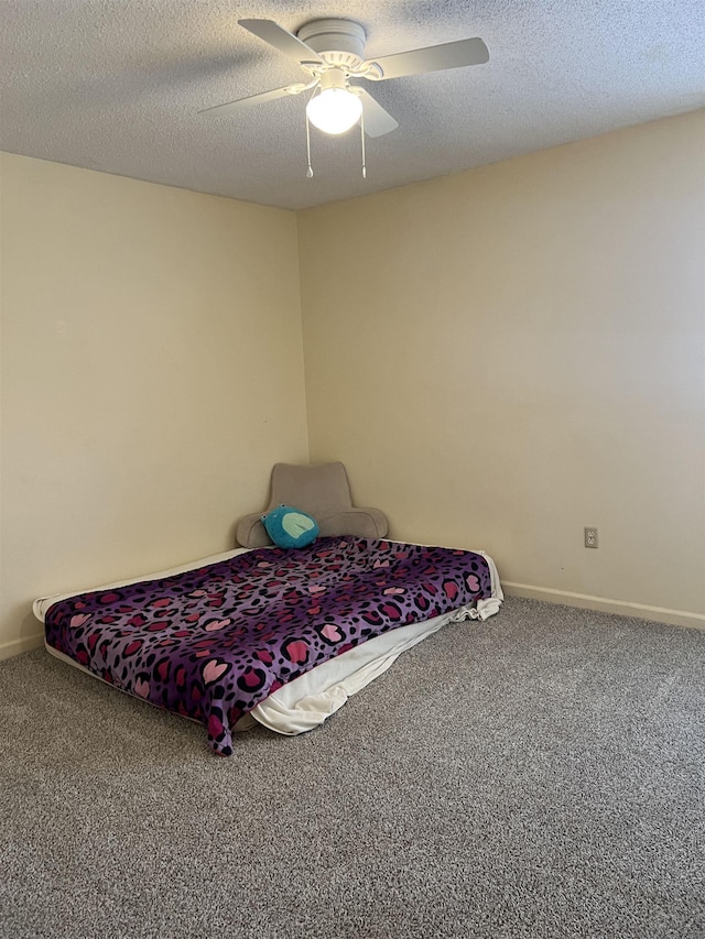unfurnished bedroom with a textured ceiling, a ceiling fan, baseboards, and carpet floors