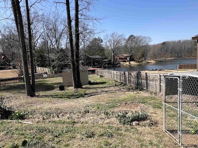 view of yard featuring a water view, a storage shed, an outdoor structure, and fence