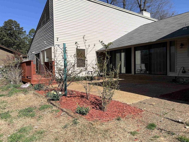 view of side of property with a chimney and a deck