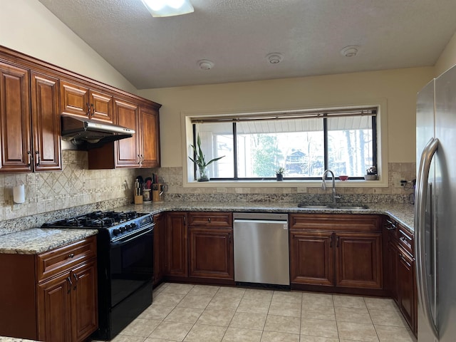 kitchen with light tile patterned floors, a sink, vaulted ceiling, under cabinet range hood, and appliances with stainless steel finishes