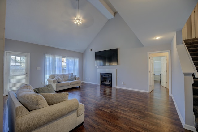 living room with dark wood-type flooring, ceiling fan, stairs, a wealth of natural light, and a glass covered fireplace