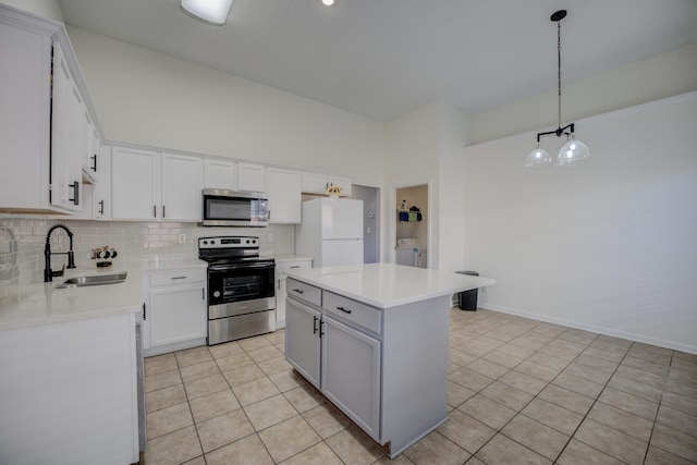 kitchen with a sink, washing machine and dryer, appliances with stainless steel finishes, light tile patterned flooring, and decorative backsplash