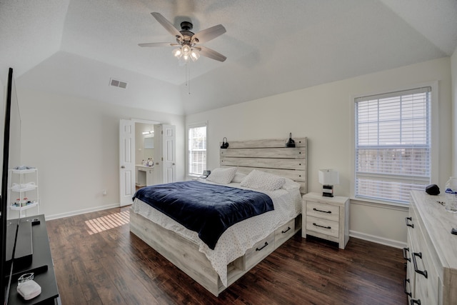 bedroom with baseboards, visible vents, lofted ceiling, dark wood-type flooring, and a raised ceiling