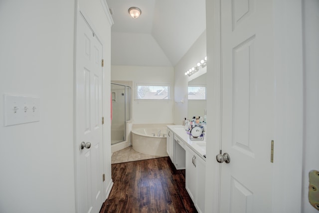 full bath with a stall shower, wood finished floors, a bath, vanity, and vaulted ceiling