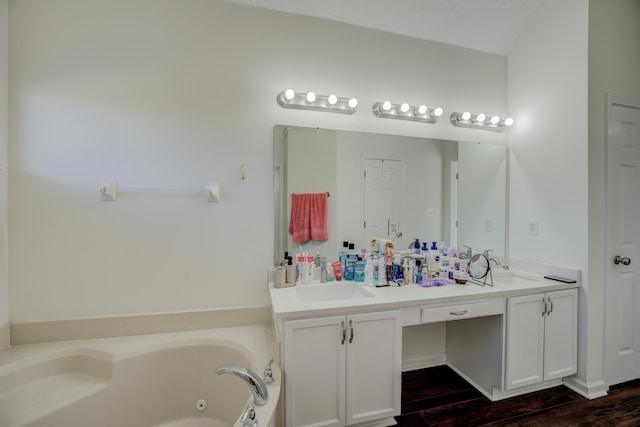 full bathroom featuring a sink, double vanity, wood finished floors, and a whirlpool tub