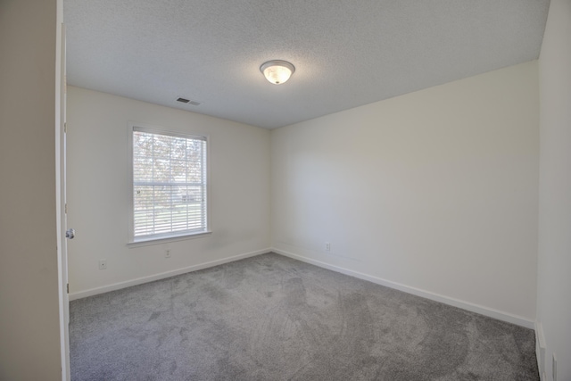 carpeted spare room featuring visible vents, baseboards, and a textured ceiling