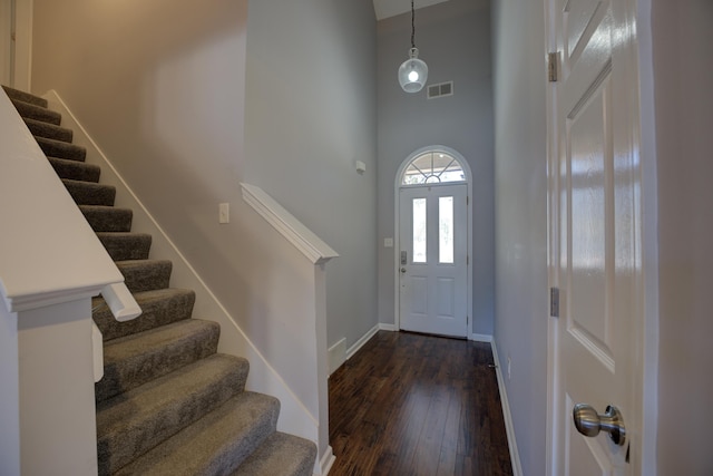 entrance foyer featuring baseboards, visible vents, a high ceiling, dark wood-style flooring, and stairs