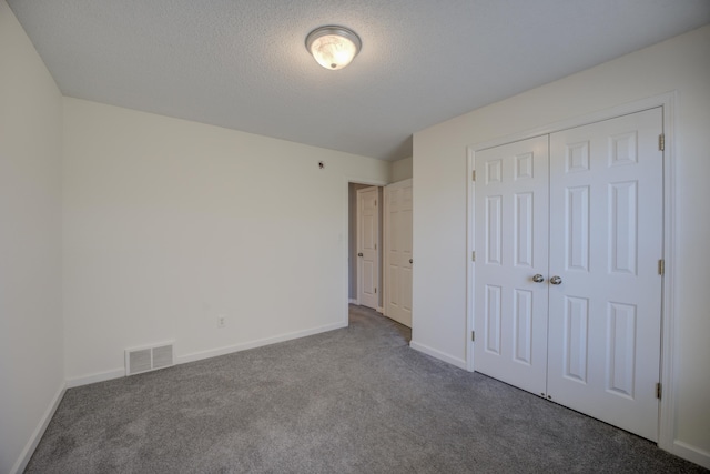 unfurnished bedroom with baseboards, visible vents, carpet floors, a closet, and a textured ceiling