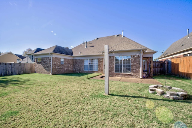 rear view of property featuring a lawn, brick siding, a fenced backyard, and a shingled roof