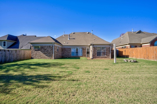 back of house featuring a fenced backyard, brick siding, and a yard