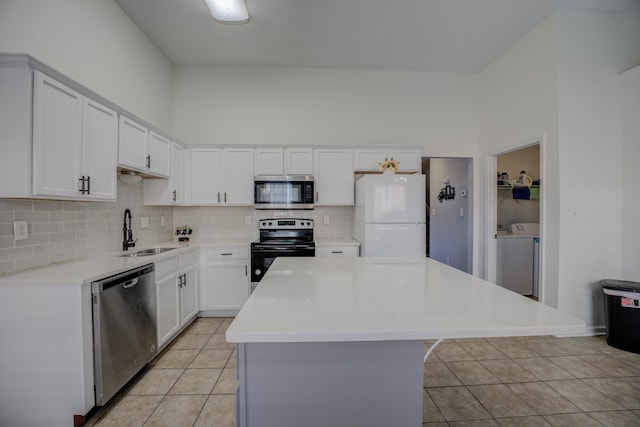 kitchen featuring a kitchen island, washer and clothes dryer, light tile patterned floors, stainless steel appliances, and a sink