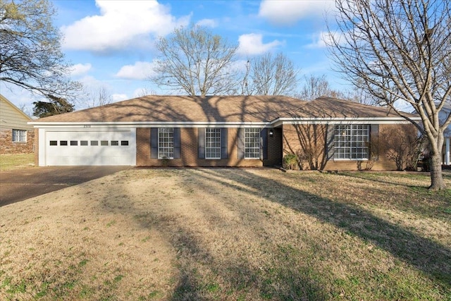 single story home featuring a front yard, brick siding, concrete driveway, and an attached garage