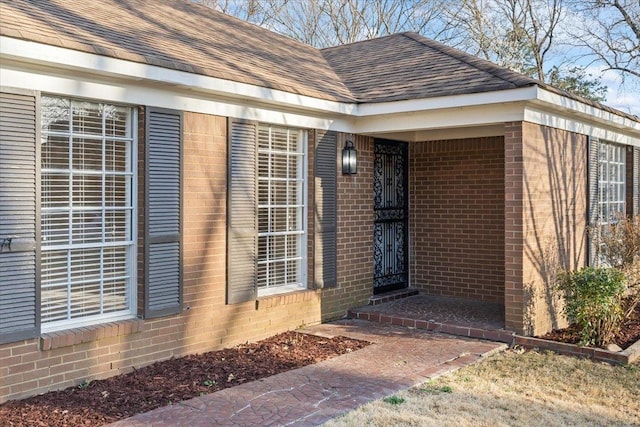 property entrance with brick siding and roof with shingles