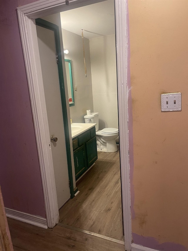 bathroom featuring toilet, vanity, baseboards, and wood finished floors