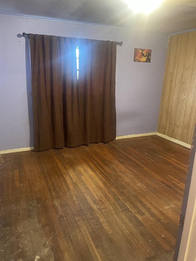 spare room featuring baseboards and wood-type flooring