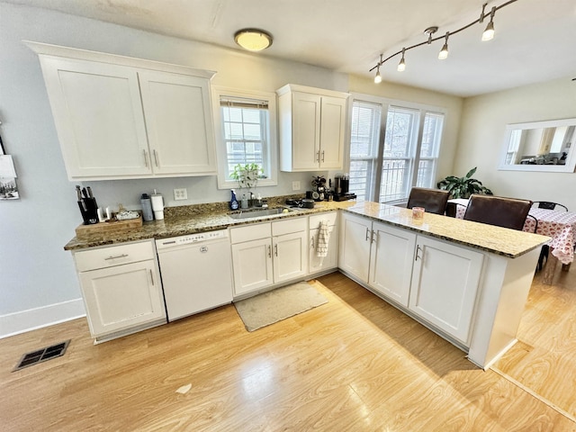 kitchen with visible vents, light wood finished floors, a peninsula, white cabinets, and dishwasher