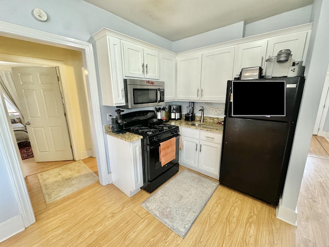 kitchen featuring black appliances, baseboards, light stone countertops, light wood-type flooring, and white cabinetry