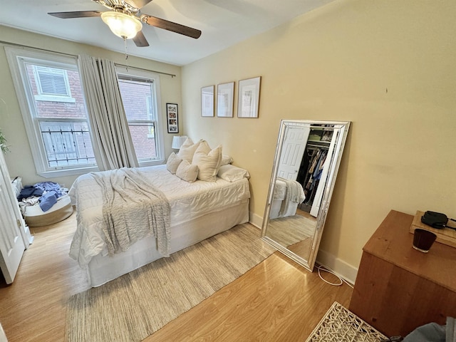 bedroom featuring a closet, baseboards, a ceiling fan, and wood finished floors