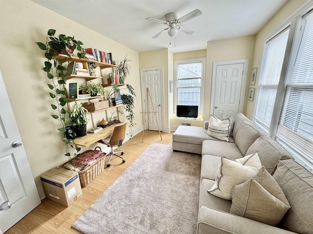 office area with baseboards, light wood-style floors, a healthy amount of sunlight, and a ceiling fan