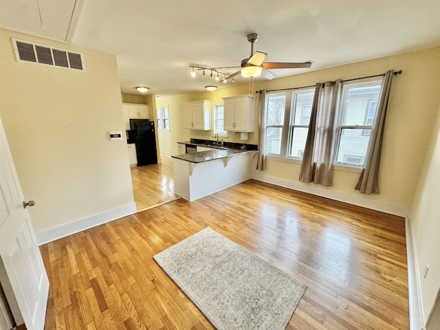 kitchen featuring a ceiling fan, visible vents, a peninsula, freestanding refrigerator, and white cabinets
