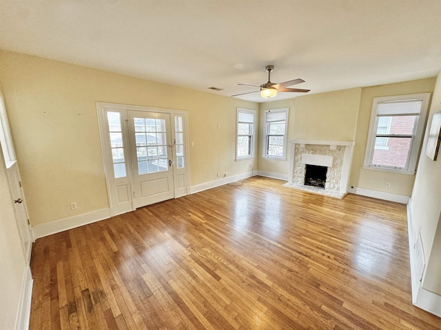 unfurnished living room featuring light wood finished floors, a healthy amount of sunlight, and ceiling fan