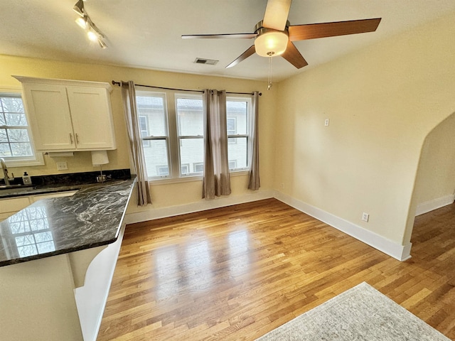 interior space featuring visible vents, track lighting, baseboards, light wood-style floors, and a ceiling fan