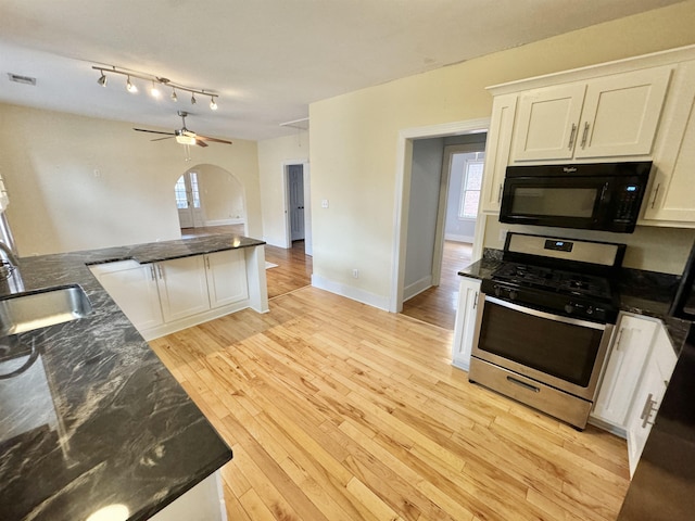 kitchen featuring a sink, gas stove, white cabinets, black microwave, and light wood finished floors