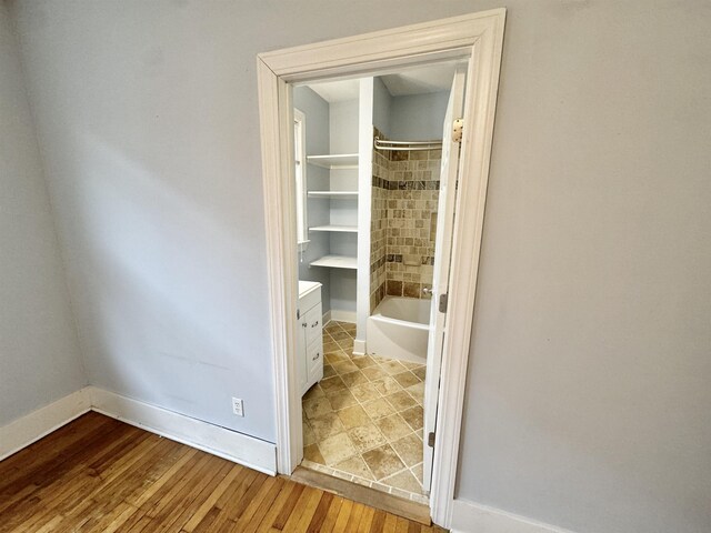 interior space featuring baseboards, bathtub / shower combination, and hardwood / wood-style flooring