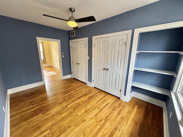 unfurnished bedroom with visible vents, two closets, light wood finished floors, baseboards, and ceiling fan