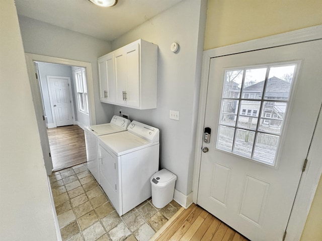 laundry area featuring stone tile flooring, cabinet space, baseboards, and washer and clothes dryer