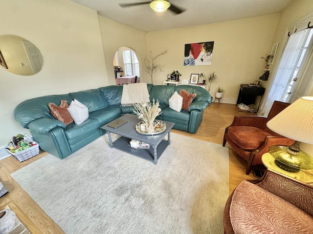 living area featuring wood finished floors, arched walkways, and ceiling fan