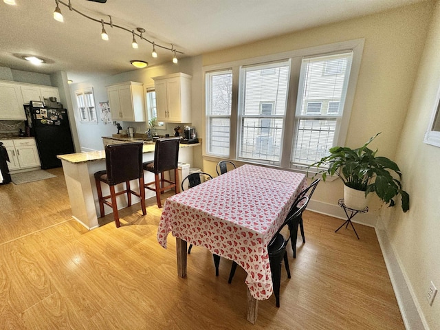 dining space with baseboards and light wood-style flooring