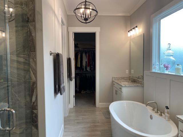 full bathroom with plenty of natural light, an inviting chandelier, a shower stall, and crown molding