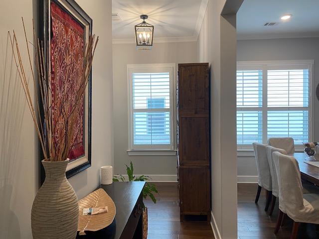 office space with an inviting chandelier, crown molding, a healthy amount of sunlight, and dark wood-style flooring