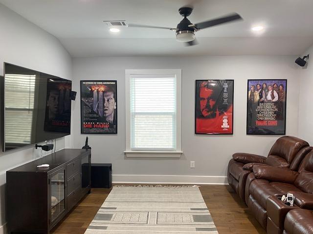 living area featuring visible vents, baseboards, a ceiling fan, and wood finished floors