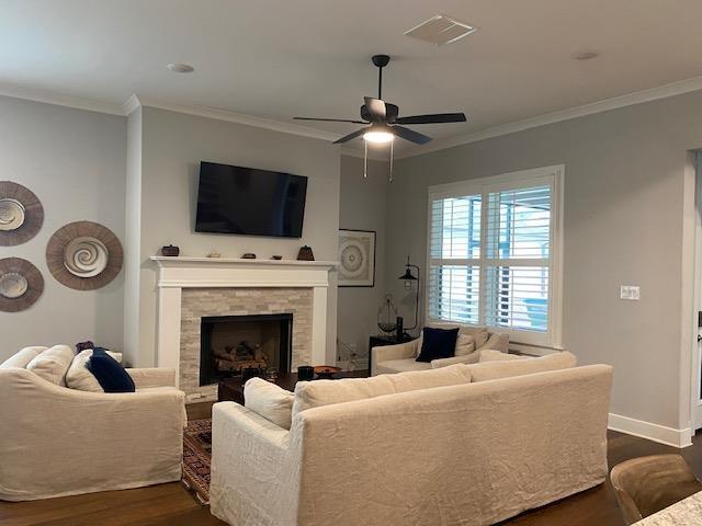 living area featuring dark wood-type flooring, ornamental molding, and a ceiling fan