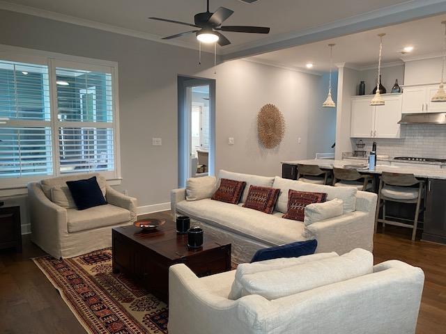 living area with dark wood finished floors, baseboards, crown molding, and ceiling fan